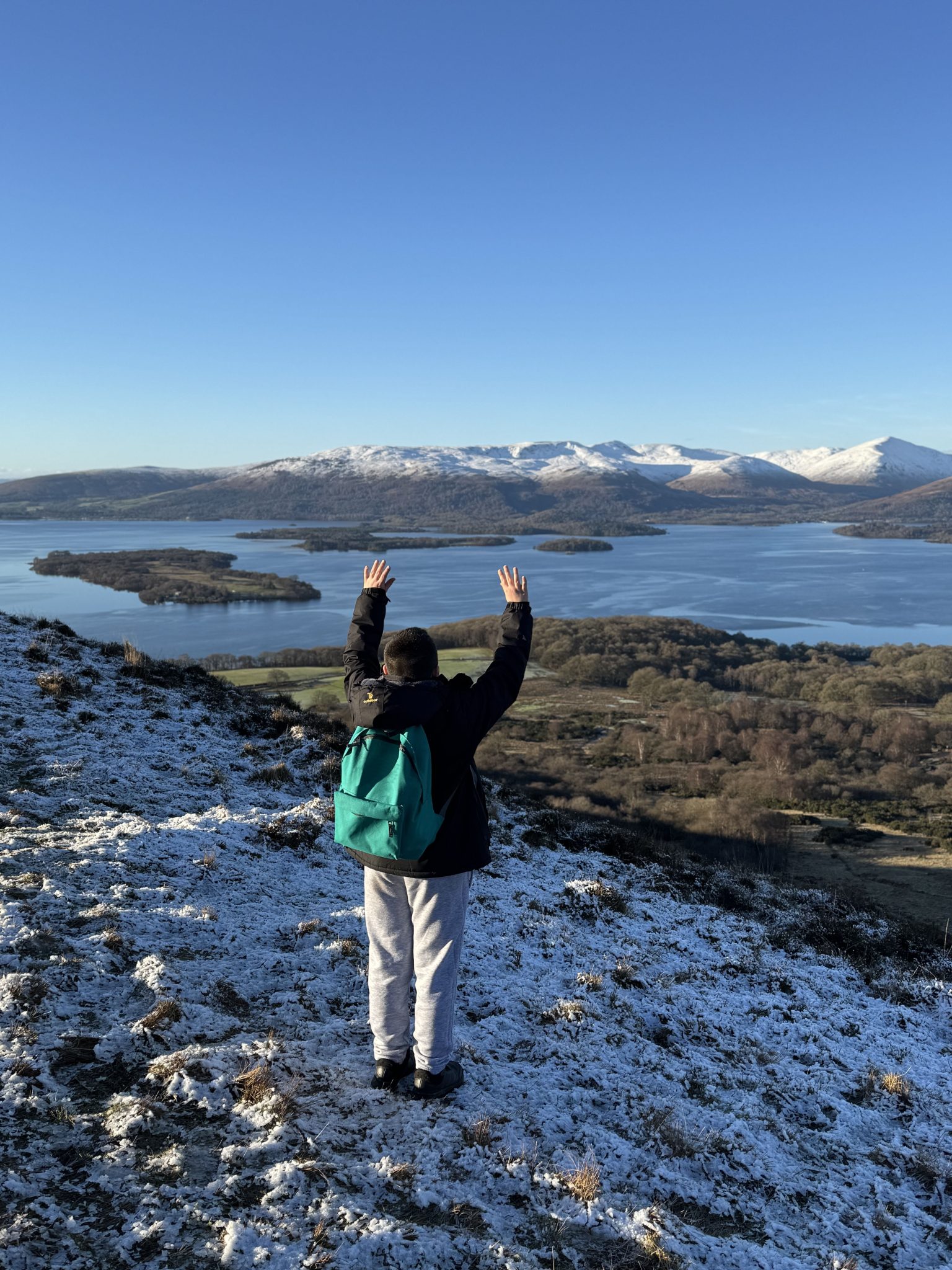Young boy on Conic Hill with arms raised