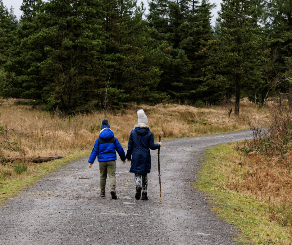 Young boy and woman on a a forest walk with backs toward camera.
