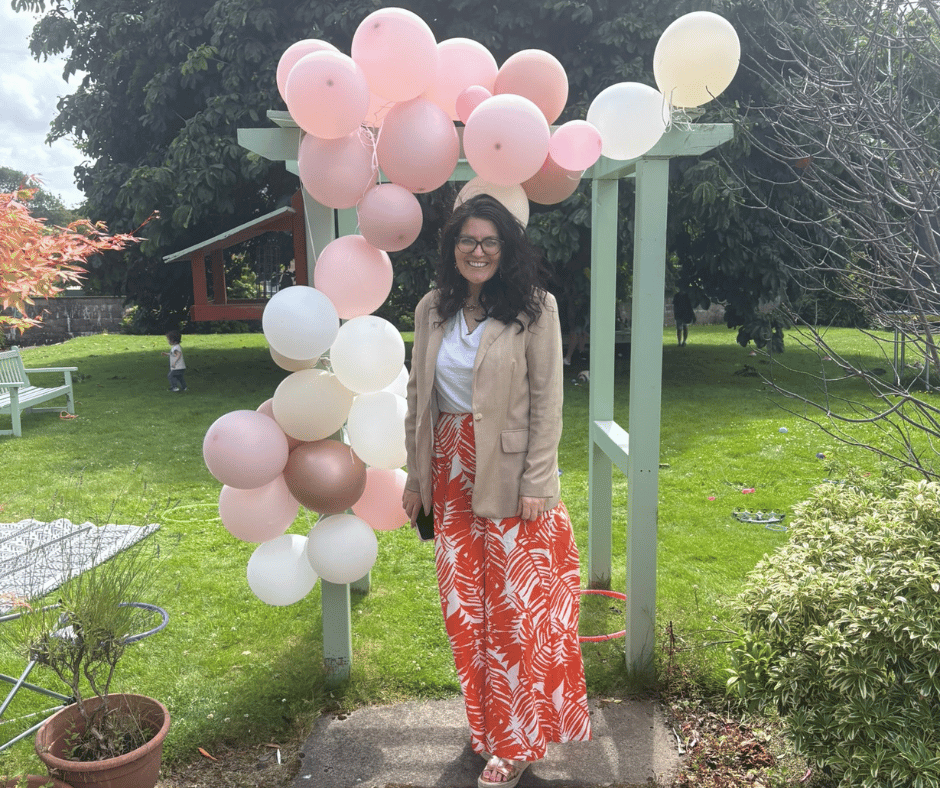 Woman standing in garden in front of pergola decorated with balloons