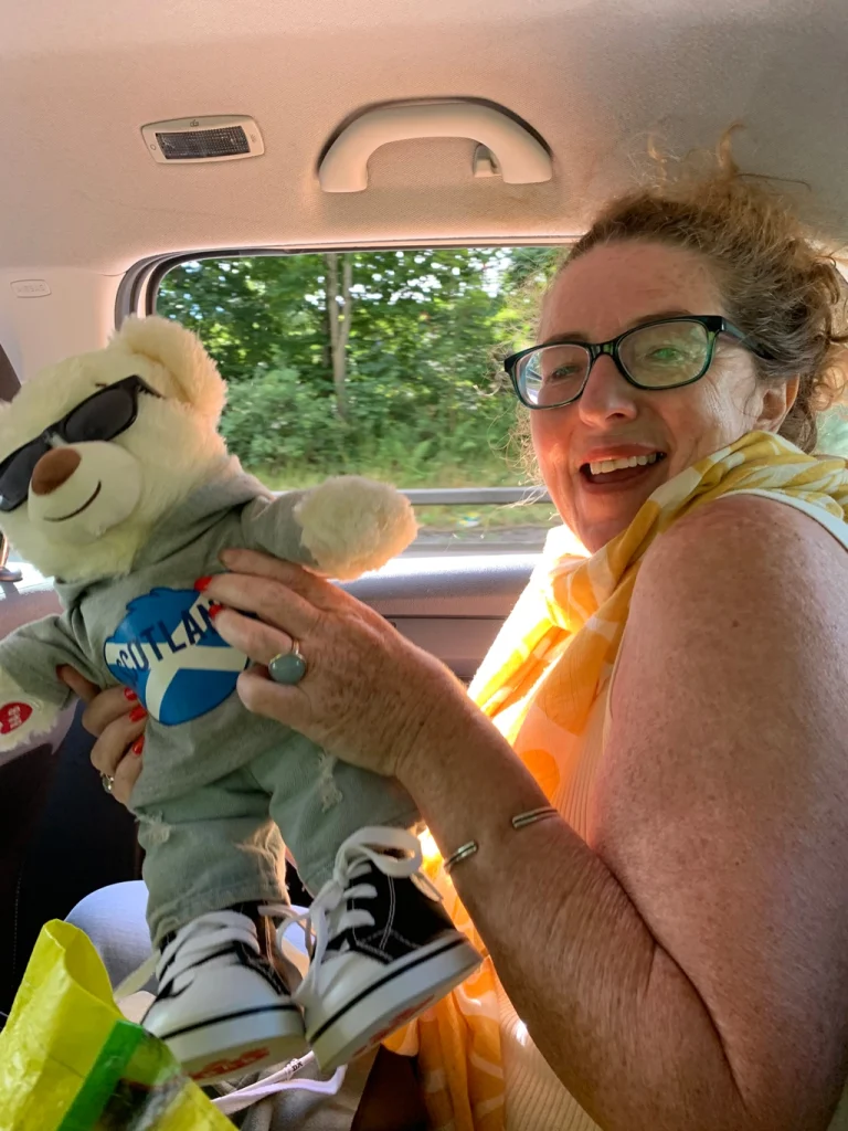 female foster parent with big smile in a car holding a teddy bear