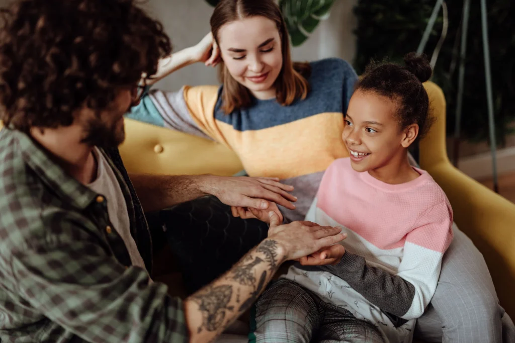 young girl laughing with foster family on sofa