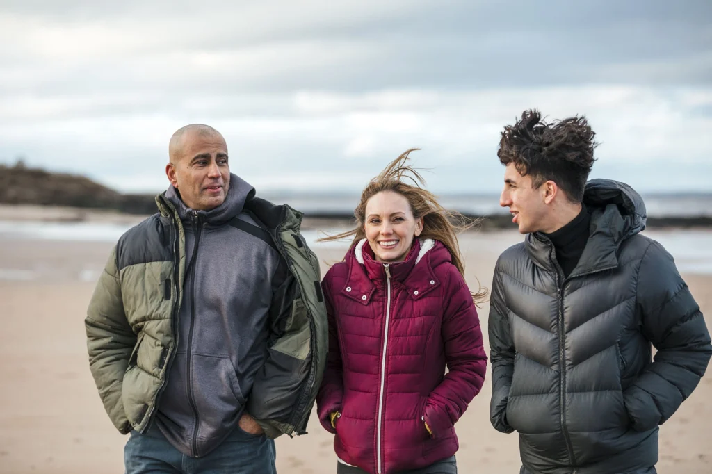 foster parents walking with a child on the beach