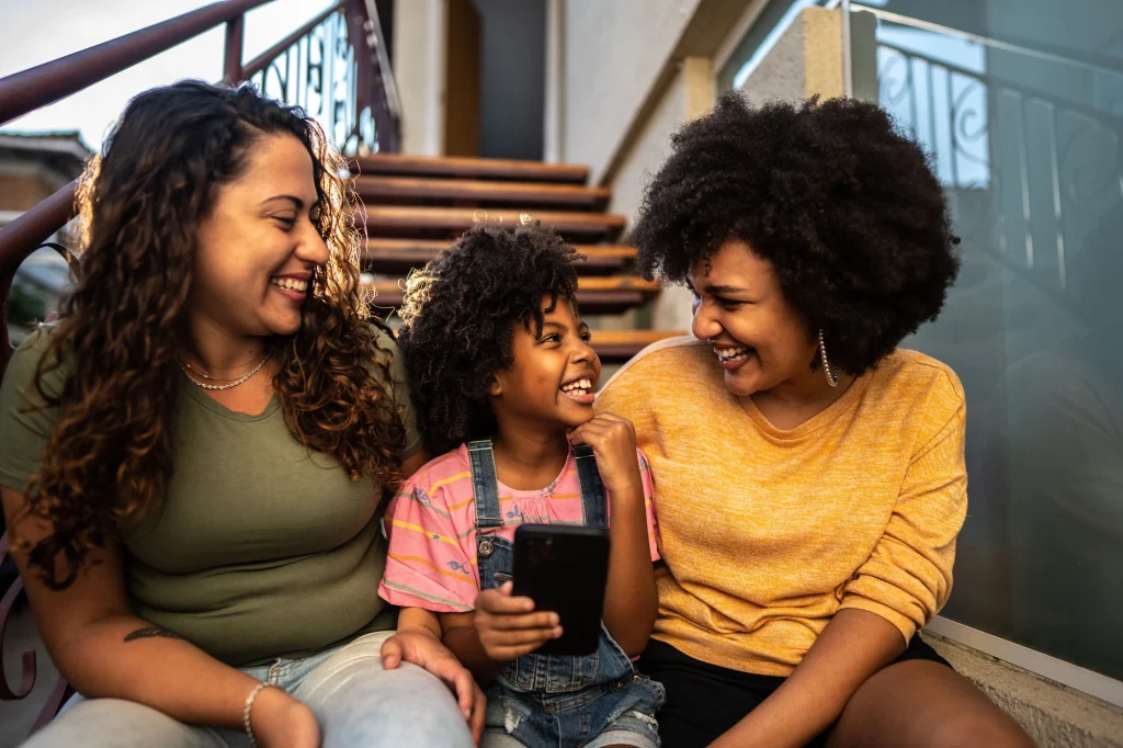 two foster care women with child laughing on a staircase