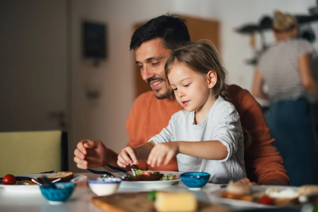 male foster carer and young girl eating food at home